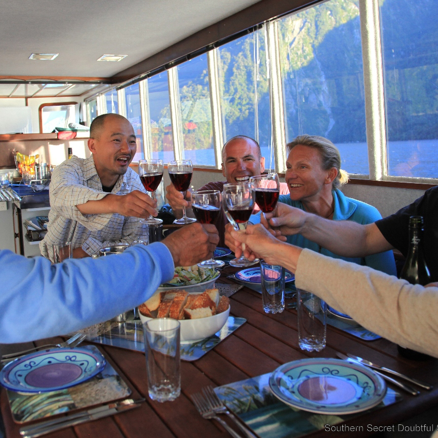 A group of six guests gathered around the dining table of the Southern Secret making a toast together with red wine.
